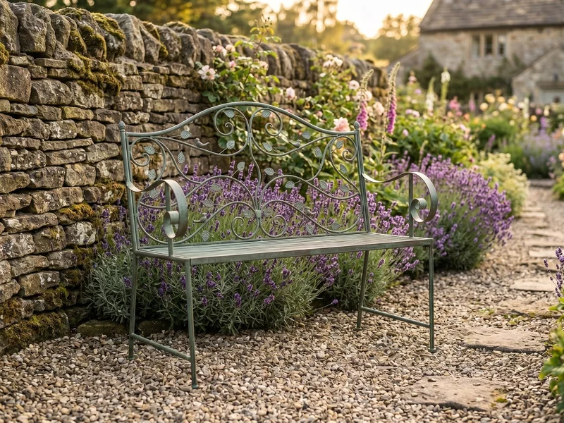 A wooden garden bench tucked beside a flower-filled perennial border with roses and catmint spilling toward a narrow path